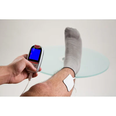 Hand holding a TENS unit connected to an iSock conductive sock worn on a leg