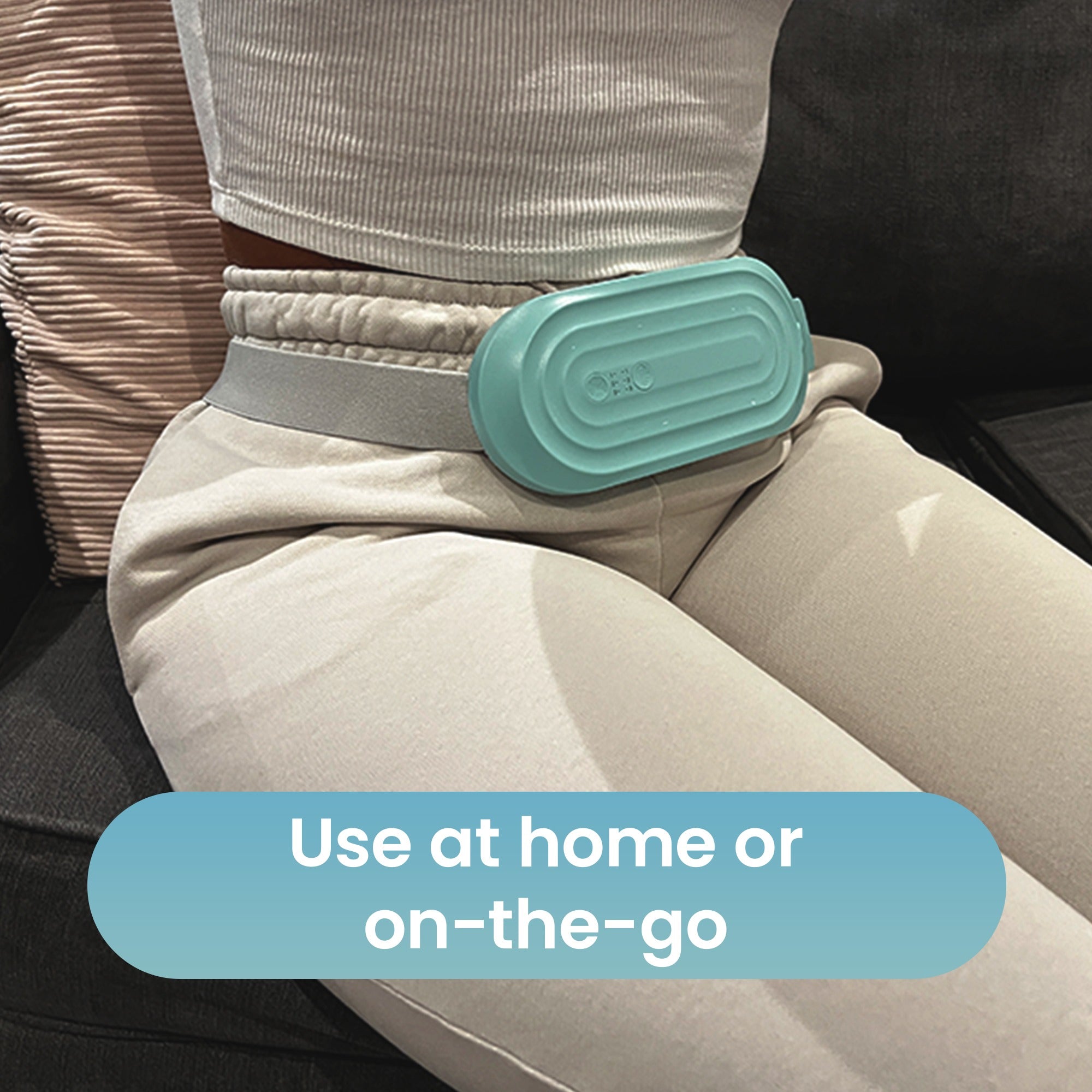 Woman seated wearing the Ova Therma belt around her waist, for use at home or on the go
